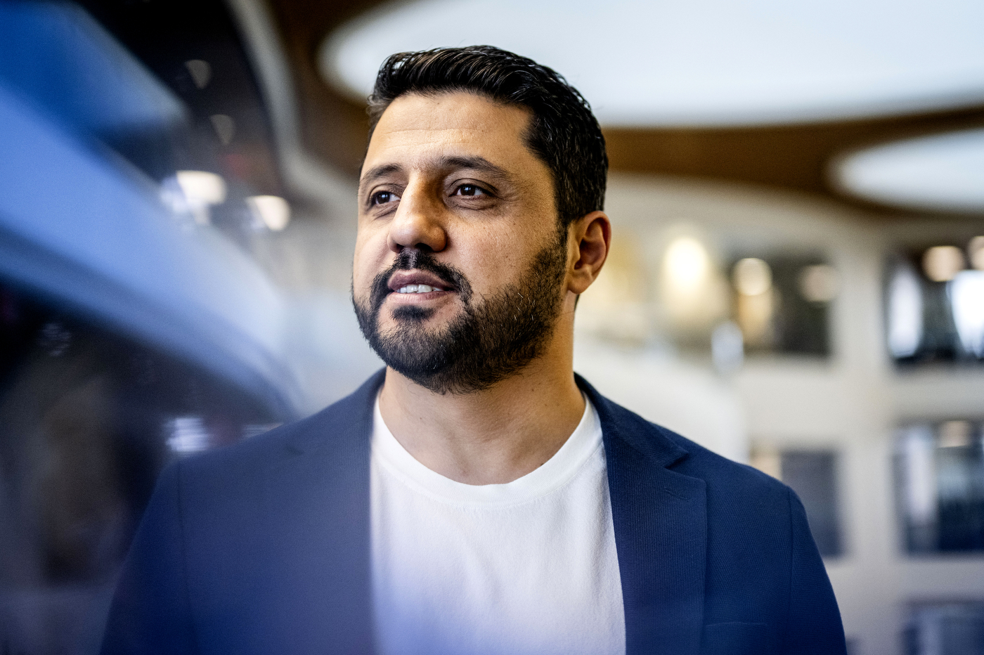 Portrait of Alper Koparan wearing a blue blazer over a white t-shirt.
