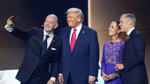 Getty Images Gianni Infantino taking a selfie on stage with Donald Trump, Claudia Sheinbaum and Mark Carney.