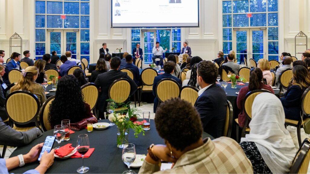 a crowd of people seated, watching a panel of speakers at the Finance Sector Summit