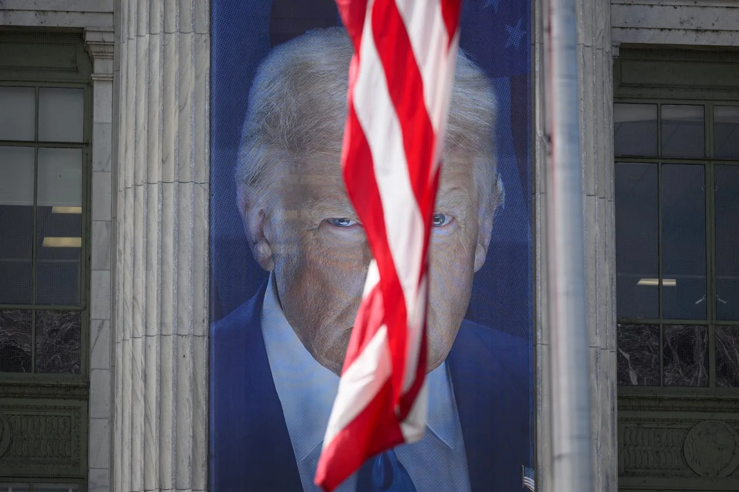 A banner showing an image of U.S. President Donald Trump is seen behind a U.S. flag outside a U.S. Department of Agriculture building in Washington.
