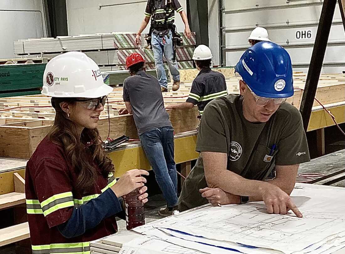 High school student June Baker and teacher Darrin Rassmusen study plans for a modular home students are helping to build at a city-owned factory in Boulder, Colorado