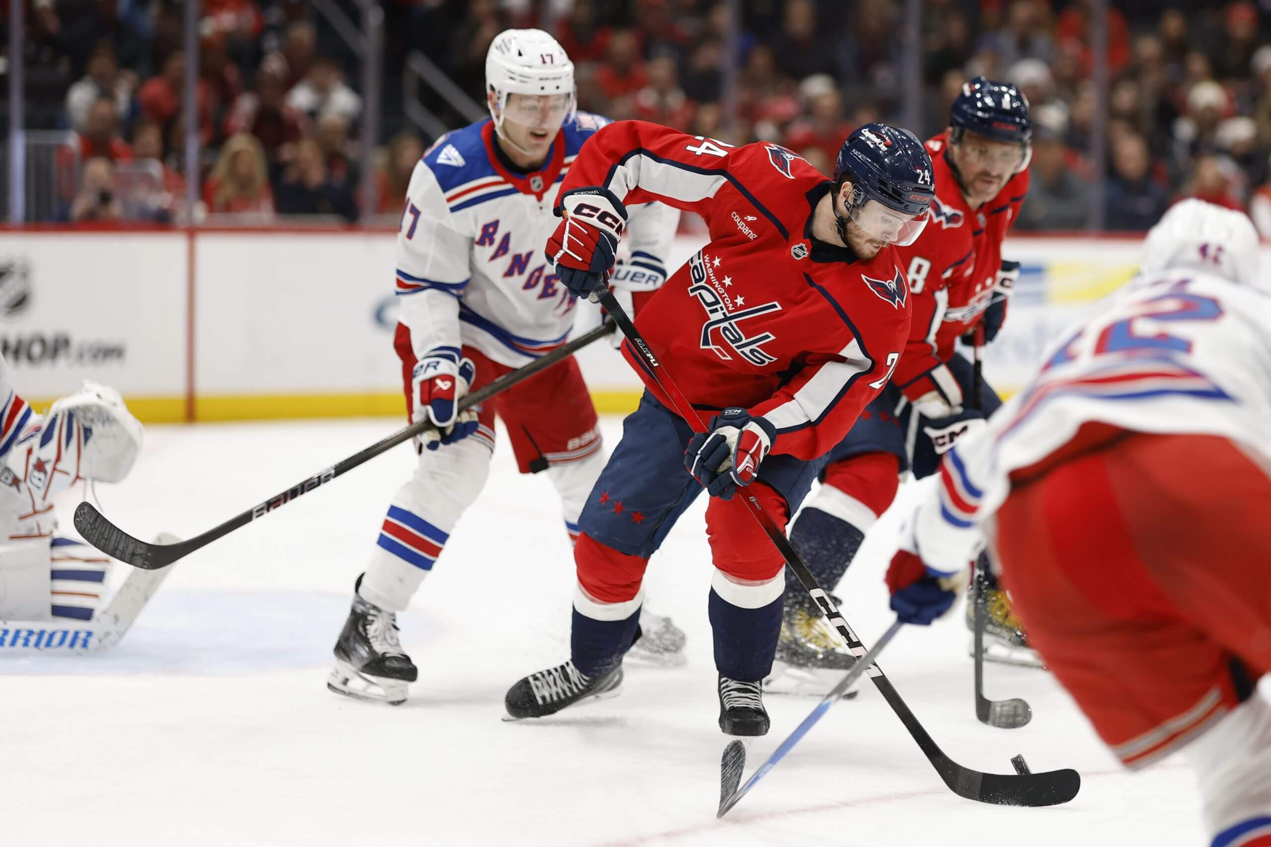 Connor McMichael flips the puck to Alex Ovechkin while surrounded by Rangers.