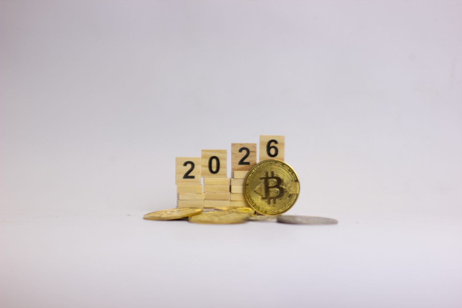 Scrabble numbers 2026 arranged on a rising platform beside a Bitcoin coin, symbolizing future growth, digital finance, and upcoming market trends