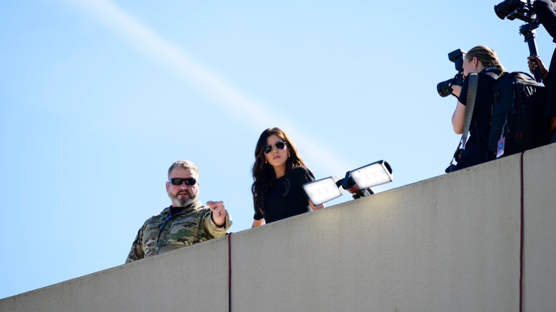 U.S. Homeland Security Secretary Kristi Noem observes the scene of ongoing protests at the Immigration and Customs Enforcement facility.