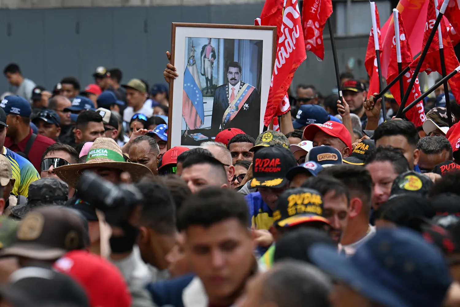 A crowd of protesters with a framed portrait of Maduro seen at center.