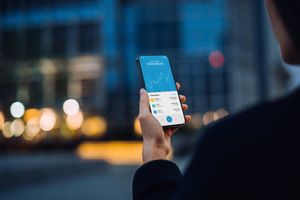 Woman holding a phone that is showing Bitcoin price chart over time