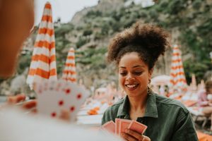Two women playing cards on a beach